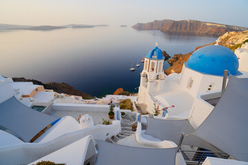 street of traditional greek village Oia of Santorini, with blue domes against Aegan sea and caldera, Greece, web banner format