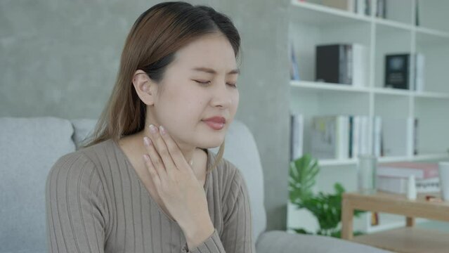 Aisa woman put her hand on her neck due to a sore throat. female tonsillitis causes a inflammation. treated by taking water, taking antibiotics, consult a doctor, virus, corona virus, Influenza, flu