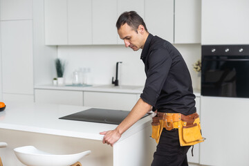 Man electrical repairs kitchen surface apartment. Installing hob in countertop. Man bought new...