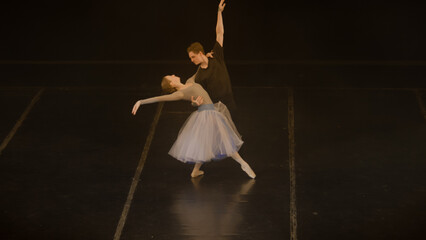 Graceful ballet dancers practice lifts and spinning ballet movements, rehearse choreography on...