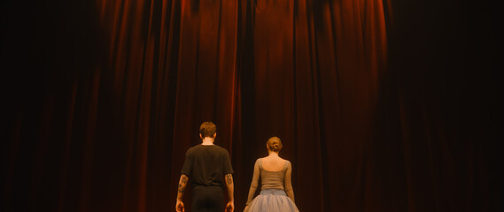 Curtains open, ballet dancers come out and perform dance on classic theater stage illuminated by spotlights. Dance partners practice at choreography rehearsal for theatrical ballet performance.
