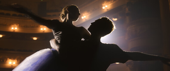 Man and woman dance and practice ballet lifts during choreography rehearsal on theater stage...