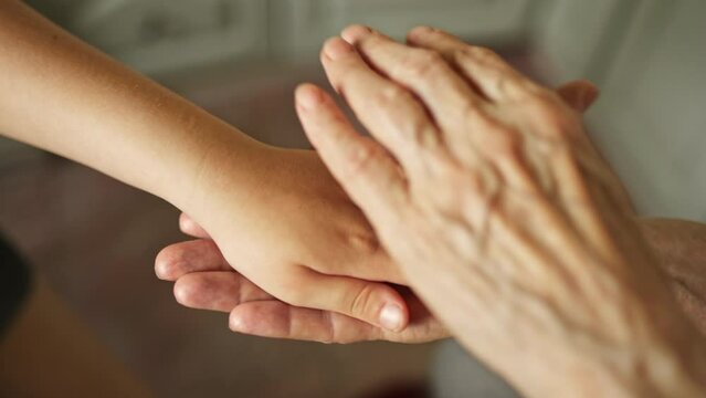 Senior grandmother woman holds  kid hands and provides support. The concept of family caring for old people.