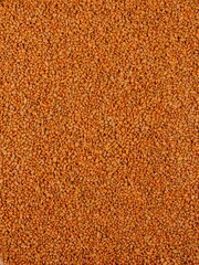 Vertical shot of small orange grains of sand for backgrounds