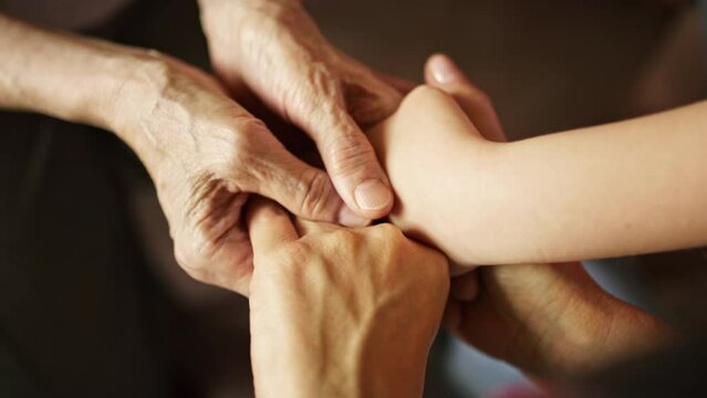 Woman and kid holds the hands of an old senior grandmother strokes them and provides support. The concept of family caring for old people.
