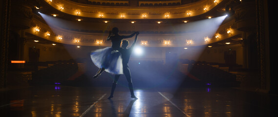 Couple of classical ballet dancers practice on theatre stage before performance. Man in training...