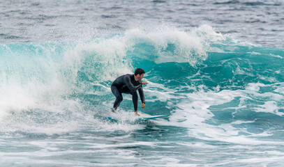 Athletic young man surfing inside a wave in a wetsuit in Tenerife