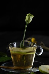 Vertical shot of a cup of spiced tea with a beautiful rose bud and a slice of apple