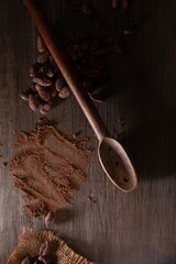 Top view of cocoa powder and beans with a spoon on the table