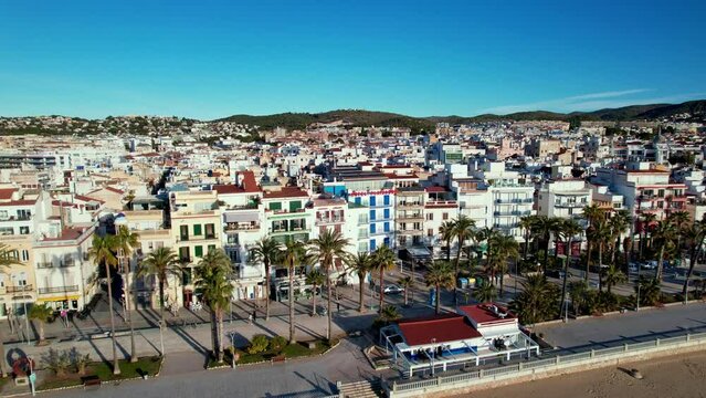 Panoramic aerial drone view of coastal village, Sant Bartomeu i Santa Tecla de Sitges during sunny day in Sitges, town near Barcelona in Catalonia, Spain. It is famous for its beaches and nightlife