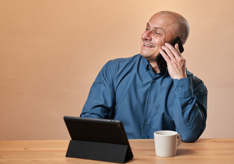 Cheerful businessman speaking on cellphone while at his desk