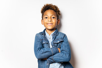 Cute smiling boy between 5-6 years old with dark skin with afro hair posing on a white background....
