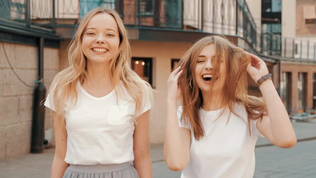 Two young beautiful blond smiling hipster girls in trendy summer clothes. Sexy carefree women posing on street background. Positive models having fun. Showing good relationship. Hugging