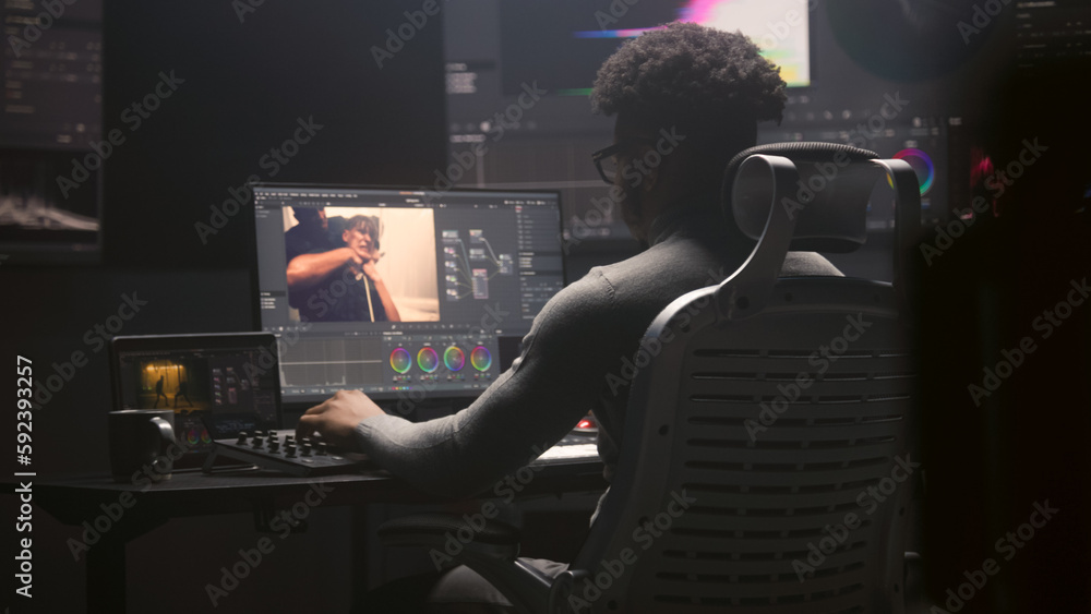 Poster african american film editor does color grading on computer in modern studio. big monitors with rgb 