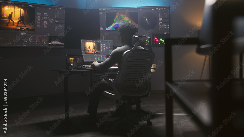 Poster handheld shot of african american colorist doing color grading on computer in modern studio. multipl
