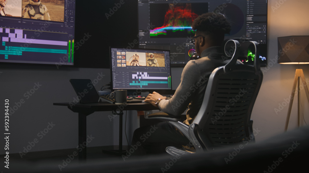 Poster african american colorist makes color grading in video editing software. multiple monitors with spac