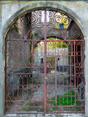 Curved gateway with closed metal gate preventing access to ruins do convento de Monchique.