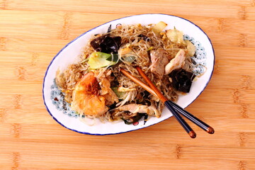Asian rice noodle dish with shrimp, chicken and vegetables, top view