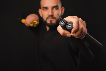 Close up nice shot of a man holding nunchaku near the camera with selective focus.