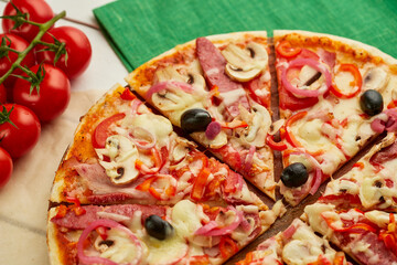 Freshly baked pizza with smoked sausages, red pepper, mushrooms, onion and olives served on wooden background with tomatoes, sauce and herbs. Food delivery concept. Restaurant menu