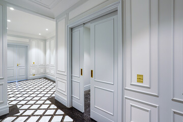 corridor with black and white contrasting tiles on the floor and white half-open doors