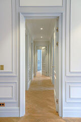 interior in an apartment with a classic luxury design, white walls with paneling and wooden parquet