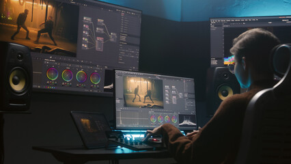 Female colorist uses color grading control panel, edits video, makes film color correction on computer in studio. Movie footage and RGB wheels on monitor. Big screens and tablet with program interface