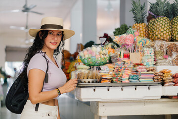 Latin woman on vacation in a market with typical sweets, stock image with copy space.