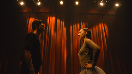 Curtains open, ballet dancers come out and perform dance on classic theater stage illuminated by spotlights. Dance partners practice at choreography rehearsal for theatrical ballet performance.