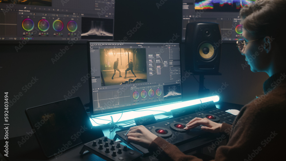 Poster female editor uses color grading control panel, edits video, makes movie color correction on compute