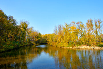 Blue river in the autumn forest on a sunny day.