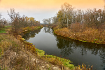 Winding river with reeds and trees along the banks.
