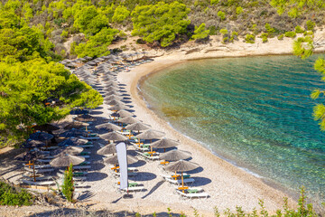 Fototapeta na wymiar Amazing emerald water of small bay in Greek islands (Spetses) and idyllic sandy beach with tents