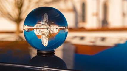 Crystal ball landscape shot with a church and reflections on a car roof at Moosfuerth, Wallersdorf, Dingolfing-Landau, Bavaria, Germany