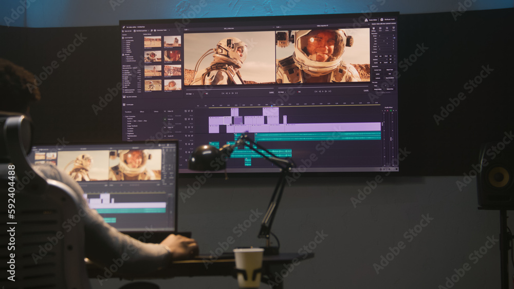 Poster african american colorist makes color grading in video editing software. multiple monitors with spac