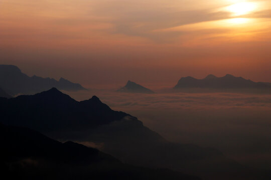 sun rises between the misty mountains and clouds
