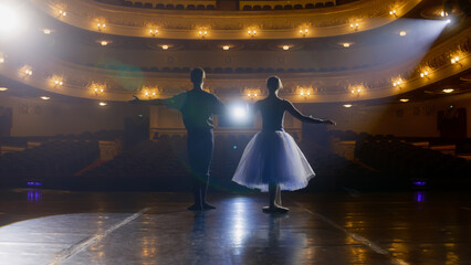 Pair of ballet dancers bow down in front of rows of seats. Ballerina with partner rehearses the end...