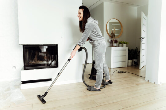 girl vacuuming,the woman dusts and cleans the mess at home,cleaning cleaner,liquidation of the mess,strong woman housewife removes trash,wet cleaning,joyful young girl dusting the floor at home