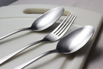 fork and spoons on a beige plank