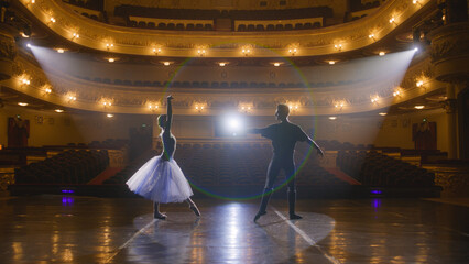 Couple of classical ballet dancers practice on theatre stage before performance. Man in training...