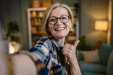 Portrait of one mature blonde caucasian woman with eyeglasses at home - obrazy, fototapety, plakaty
