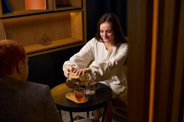 Pleasant young woman pours tea to her husband