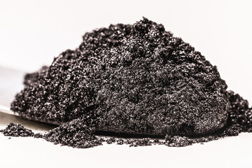 black pigment, powder for industrial or cosmetic use, isolated white background, in petri dish,...
