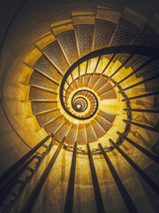Spiral staircase abstract perspective with view downstairs to infinity swirl stairs in glowing...
