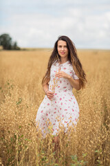 Fototapeta na wymiar A brunette woman in a white dress runs along a field