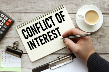 Conflict of interest text on a white page on the table. a man writes in a notebook