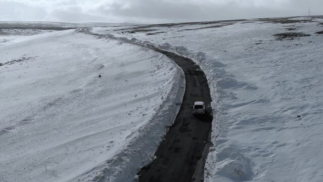 Wide Shot of Car driving on Iceland Road with Snow white Mountains