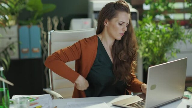 sad modern small business owner woman with back pain in the modern green office.