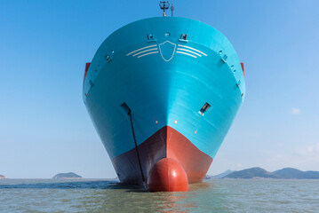 Front view of the big container ship. She is newly painted and anchored near shipyard. 