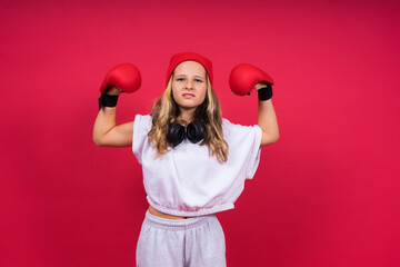 Cute little girl in boxing gloves on red background studio